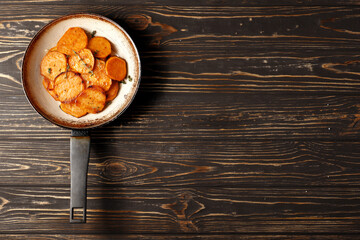 Frying pan with sweet fries on wooden table