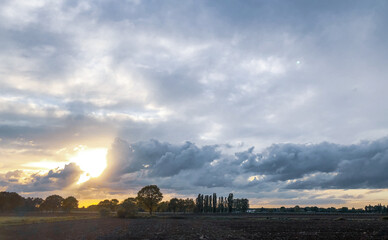 Colorful countryside sunrise or sunset over the agraric farmfields showing the dramatic colors and stormy clouds in the dark sky 