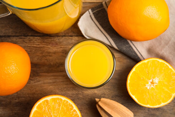 Fresh ripe oranges, reamer and juice on wooden table, flat lay