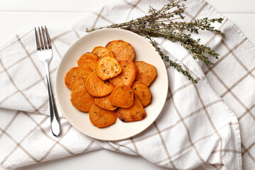 Plate with deliciously cooked sweet potatoes, rosemary, sauce and spices, herbs on a wooden table