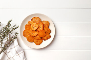 Plate with deliciously cooked sweet potatoes, rosemary, sauce and spices, herbs on a wooden table