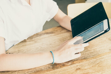 Young woman wearing white shirt, using tablet in open flip case, reading text on screen while sitting at table. Cropped shot. Digital communication concept