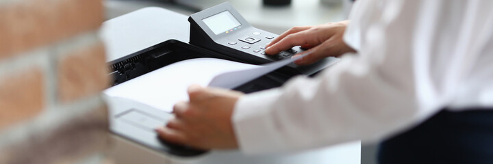 Woman in office prints documents on printer. Scanning documents at workplace concept