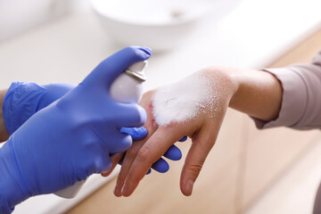 Applying burn spray onto injured skin, closeup