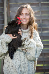 Happy young woman with a black hen