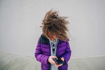 Occupied brunette woman using mobile phone and the wind blowing through her hair.
