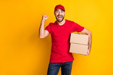 Portrait of attractive cheerful lucky guy mailman bringing parcels rejoicing isolated over bright yellow color background
