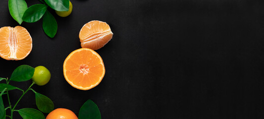 Tangerines or clementines with leaves on a black background. Top view with copy space.