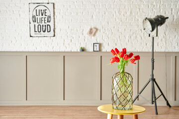 Red tulip in vase at the room, decorative interior wall background style.