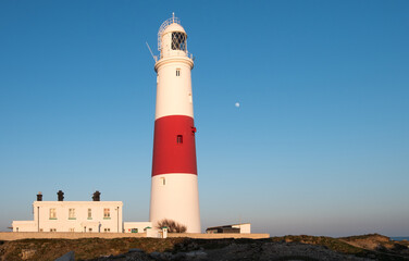 Fototapeta na wymiar Sunset on a beautiful summers evening at the iconic candy striped lighthouse at Portland Bill on the Jurassic Coast in Dorset.