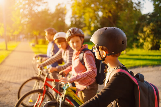 Children with rucksacks riding on bikes in the park near school