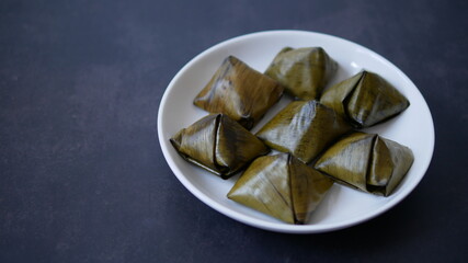 Stuffed dough pyramid dessert called Ka-Nhom-Tian isolated on black background, Thai dessert  wrapped in banana leaves 