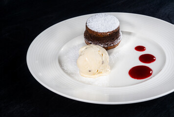 Dessert of ice cream and cupcake on a white plate on a black background