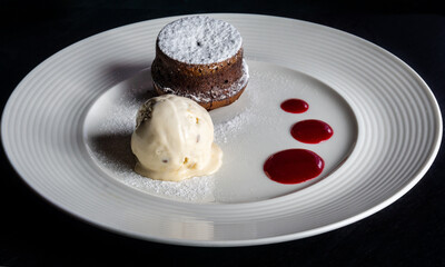Dessert of ice cream and cupcake on a white plate on a black background