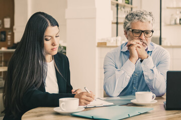 Business colleagues or partners meeting at co-working, reading agreement, using laptop. Medium shot. Teamwork or cooperation concept