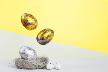 Illuminating Gold and silver Easter eggs levitation to the nest on a Ultimate Grey and yellow background. Easter concept