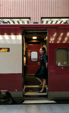 Antwerp, Belgium, September 2019, Open door on a Thalys train waiting in Antwerp Centrail Railway Station with a young female conductor welcoming the passengers