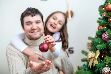 Fototapeta na wymiar Dad and daughter are decorating christmas tree