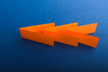 Multicolored cut paper on blue. Abstract arrows, direction signs.