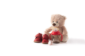 Teddy bear, pacifier,feeding bottle and shoes isolated on white background.Copy space