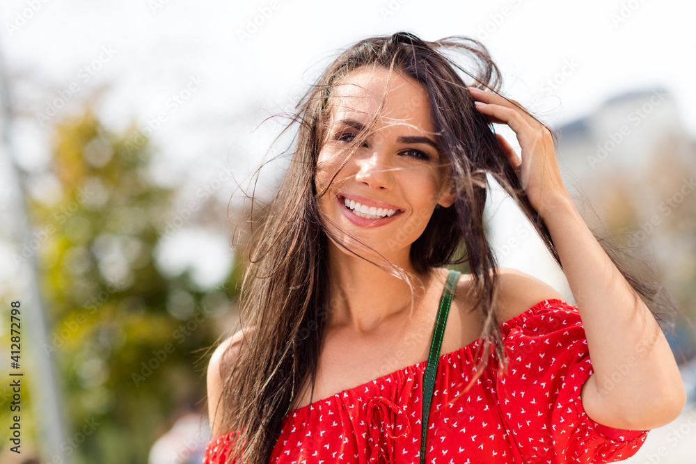 Sticker Photo portrait of smiling cheerful woman walking on summer city streets in hot windy weather in red clothes