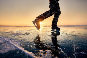 Ice skating on frozen lake at orange sunrise