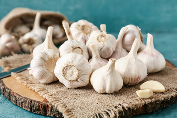 Board with fresh garlic on color background