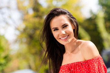 Naklejka premium Photo portrait of adorable brunette in red clothes with off-shoulders spending free time in green park in spring smiling