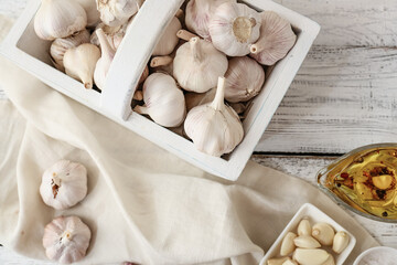 Basket with fresh garlic on light wooden background