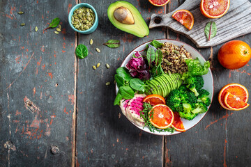 Buddha bowl of mixed vegetables, healthy and nutritious vegan meal with avocado, blood orange, broccoli, watermelon radish, spinach, quinoa, pumpkin seeds. place for text, top view