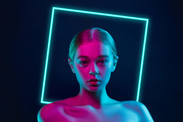 Future. Portrait of female fashion model in neon light with neoned blue glowing square on dark...