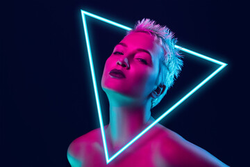Future. Portrait of female fashion model in neon light with neoned blue glowing triangle on dark...
