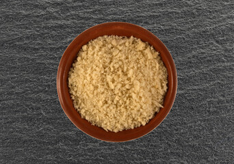 Terracotta bowl filled with white bread crumbs on a black slate background top view.