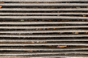 Close view of a dirty cabin air filter with old leaves dust and dirt.