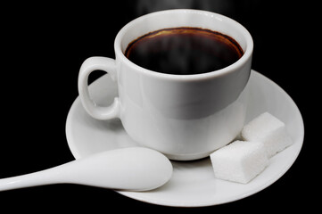 Coffee cup with sugar and spoon on a black background. Coffee is an invigorating and tonic drink. Isolate on a black background