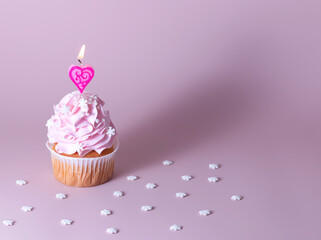 Pink muffin or cupcake for Valentine's Day, Mother's Day or Birthday, decorated with a heart shaped candle. Place for text. - Powered by Adobe