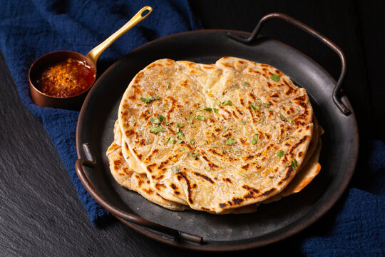 Food concept spot focus homemade Paratha, Parotta or Porotta layered flatbread  on black background with copy space