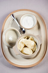 portion of ukrainian russian polish dumplings stuffed with potato in a ceramic pot served with sour cream