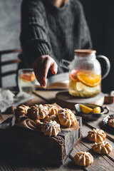 A woman reaches for a cake and drinks grapefruit tea. Healthy drink.