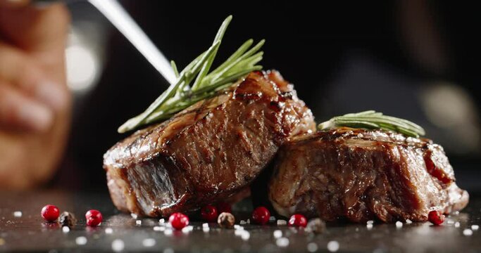 Freshly grilled meat with vegetables. Chef's hand decorates the dish with rosemary
