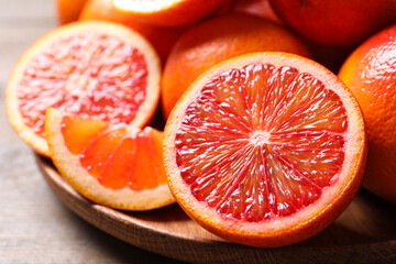 Whole and cut red oranges on wooden table, closeup