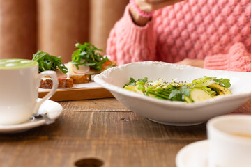 Healthy breakfast in the restaurant. Green salad, bruschetta with arugula and salmon and matcha latte