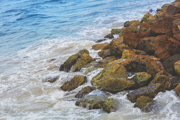 Fototapeta na wymiar Sea surf on a rocky shore with large brown stones