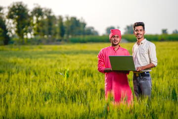 Young indian agronomist and farmer using laptop for seeing some information about farming