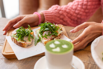 Woman in a restaurant in a cozy warm sweater wholesome breakfast with toast with arugula and salmon