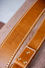 A orange leather belt lies on a brown wood diagonally close-up