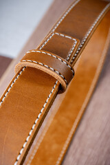 Detail of an orange leather belt lying on a brown tree close up