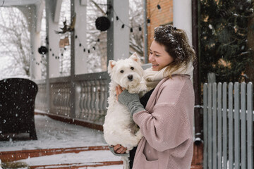 Nice laughing girl hugging adorable white dog with funny cute emotions.