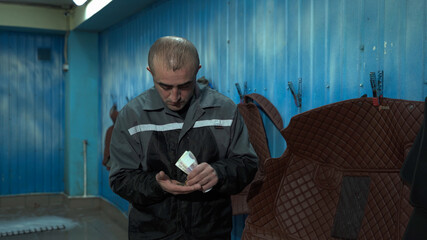 A male worker of Caucasian nationality received Russian rubles for a working day. A male worker holds money in his hands and counts it