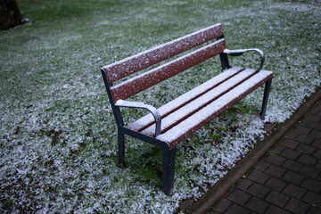 Realistic bench with snow, cold weather, frozen green grass